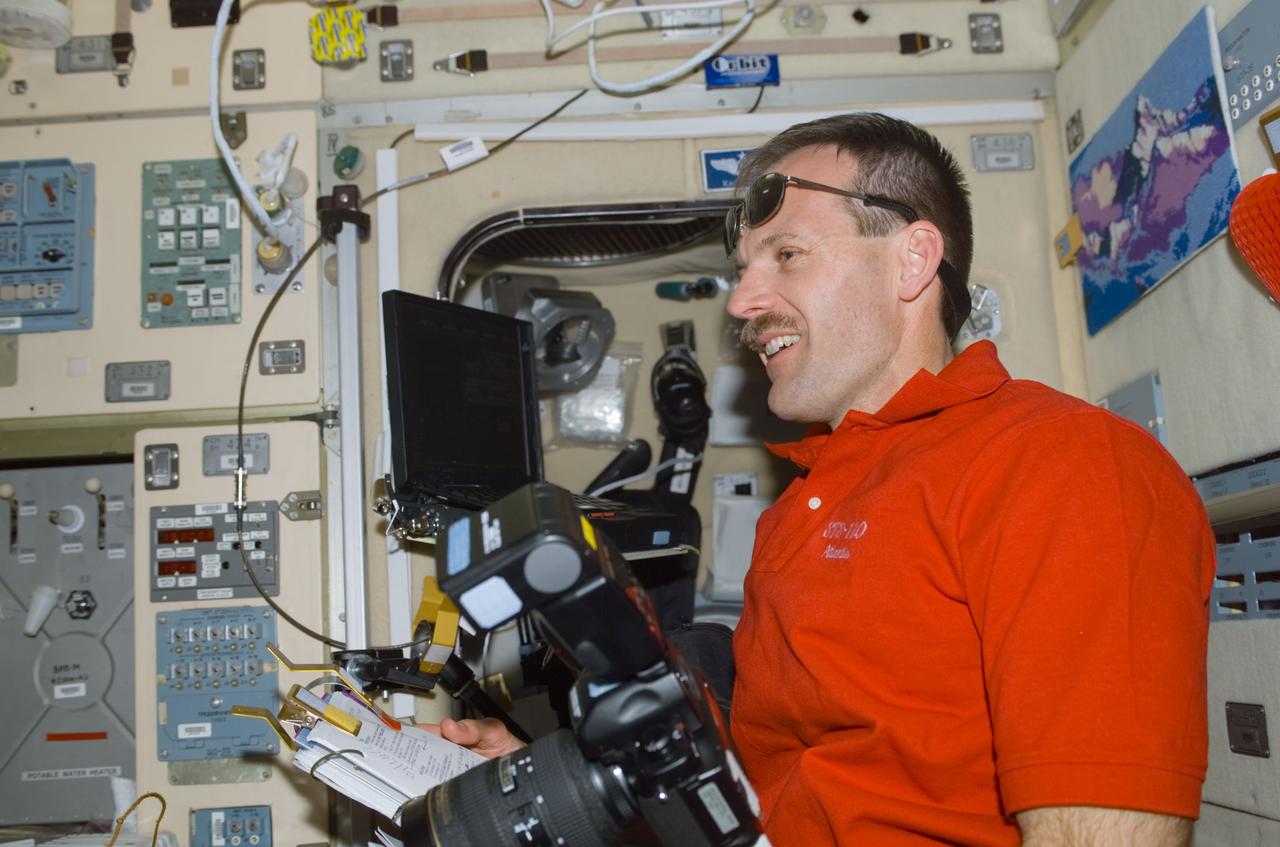 STS110-E-5131 (10 April 2002) --- Astronaut Steven L. Smith, STS-110 mission specialist, holds a still camera and a procedures checklist in the Zvezda Service Module on the International Space Station (ISS). The image was taken with a digital still camera.