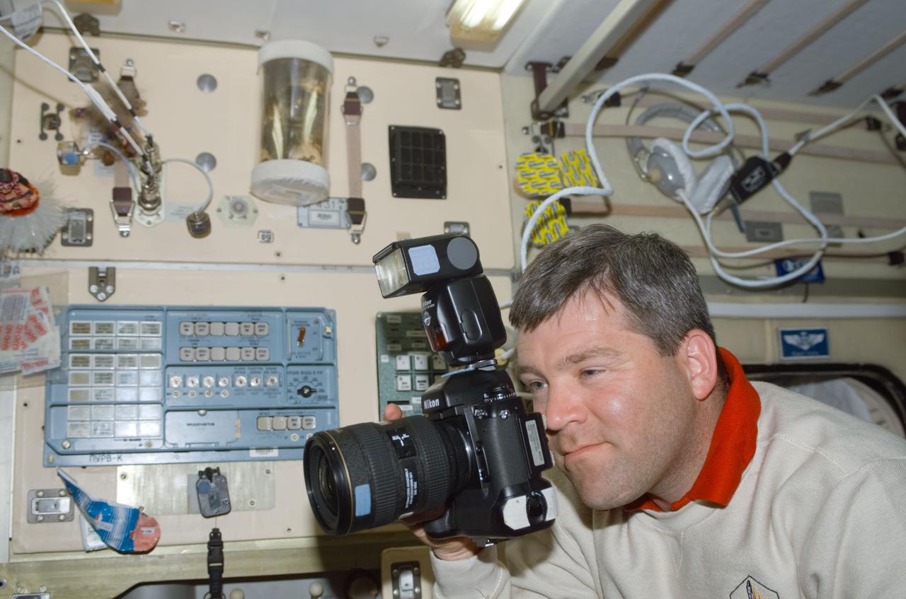 STS110-E-5134 (10 April 2002) --- Astronaut Stephen N. Frick, STS-110 pilot, uses a still camera in the Zvezda Service Module on the International Space Station (ISS). The image was taken with a digital still camera.