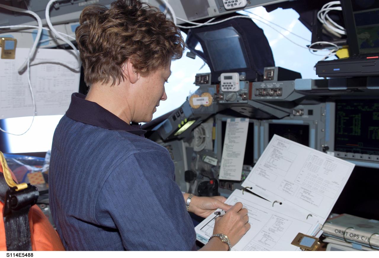 S114-E-5488 (28 July 2005) --- Astronaut Eileen M. Collins, STS-114 commander, looks over a checklist on Discovery's forward flight deck  on a day dedicated to rendezvous and docking activities with the International Space Station and followup operations.