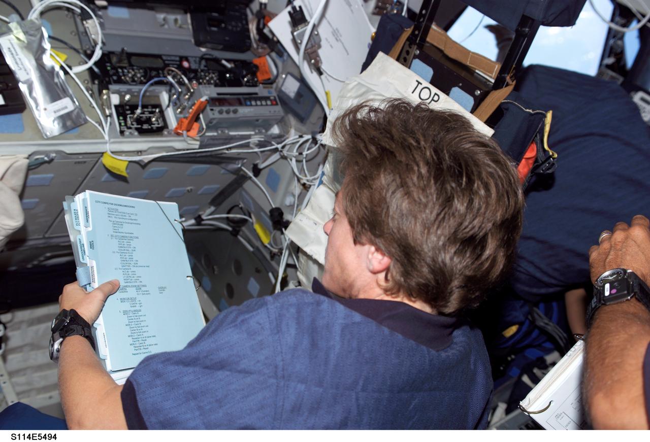 S114-E-5494 (28 July 2005) --- Astronaut Wendy Lawrence, STS-114 mission specialist, refers to a procedures checklist on Discovery's flight deck. This third day of on-orbit activities is dedicated primarily to rendezvous and docking activities and followup operations.