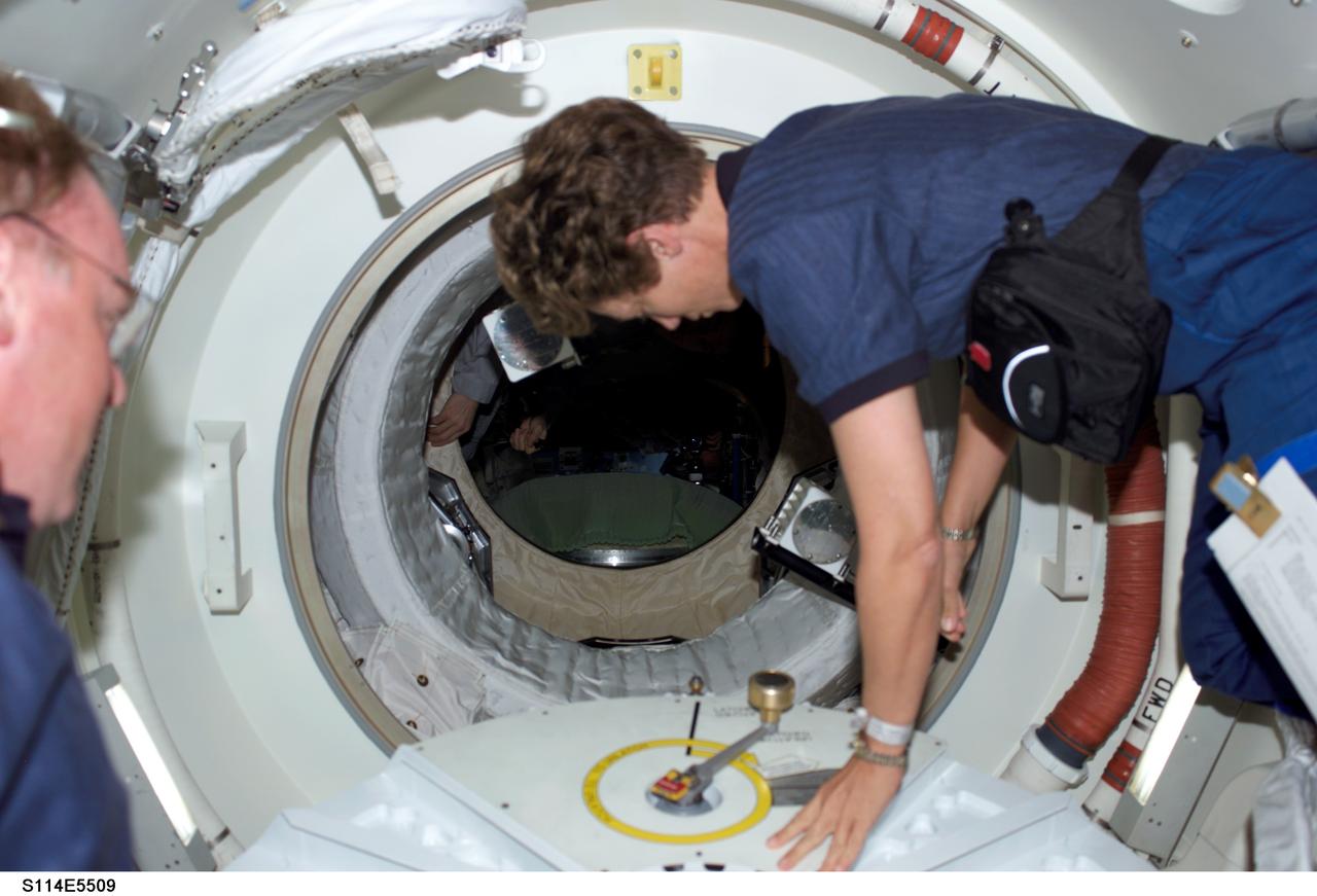 S114-E-5509 (28 July 2005) --- Astronaut Eileen M. Collins, STS-114 commander, has just opened the hatch that will lead her and the entire Discovery crew into the International Space Station. Astronaut Andrew S.W. Thomas, mission specialist, is partially visible at left edge of frame. This was just one highlight of a very busy day that earlier saw the flawless rendezvous and docking operations between the shuttle and the orbital outpost.