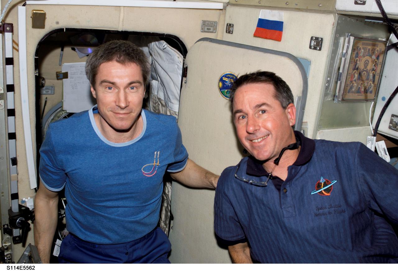 S114-E-5562 (28 July 2005) --- Russia's Federal Space Agency cosmonaut Sergei Krikalev (left) and NASA astronaut Stephen K. Robinson greet as Robinson and his STS-114 crewmates become the first human beings to interface face-to-face with the Expedition 11 crewmembers onboard the International Space Station. Earlier on this third flight day for STS-114, the Shuttle and its seven-member crew flawlessly docked with the orbiting outpost where all nine crew members will spend several days conducting joint activities.