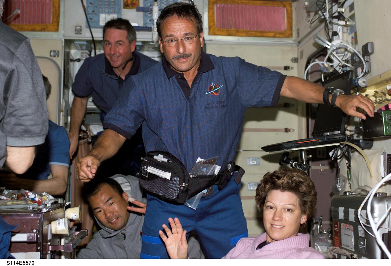 S114-E-5570 (28 July 2005) --- A pre-meal scene onboard the International Space Station depicts the associated elation of the  highly anticipated reunion of the STS-114 astronauts and the hosting  Expedition 11 crewmembers.  Astronaut Eileen M. Collins waves, as she is surrounded by mission specialist crewmates, including astronauts Stephen K. Robinson (floating in background) and Charles J. Camarda, center. Japanese Aerospace Agency astronaut Soichi Noguchi is at lower left.