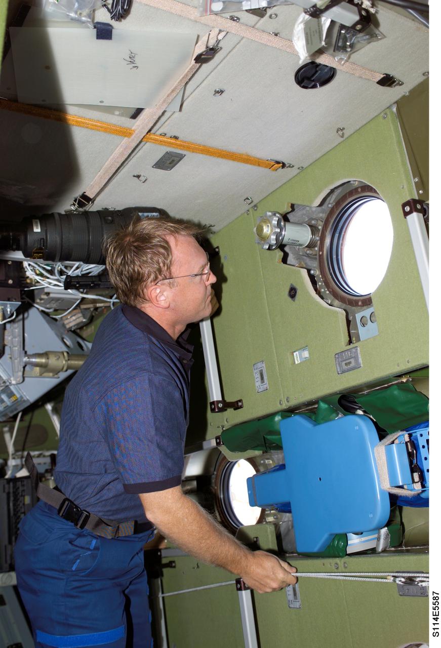 S114-E-5587 (28 July 2005) --- Astronaut Andrew S.W. Thomas looks through a window on the Zvezda Service Module soon after joining the rest of the STS-114 for its first joint visit with the Expedition 11 crewmembers aboard the International Space Station.