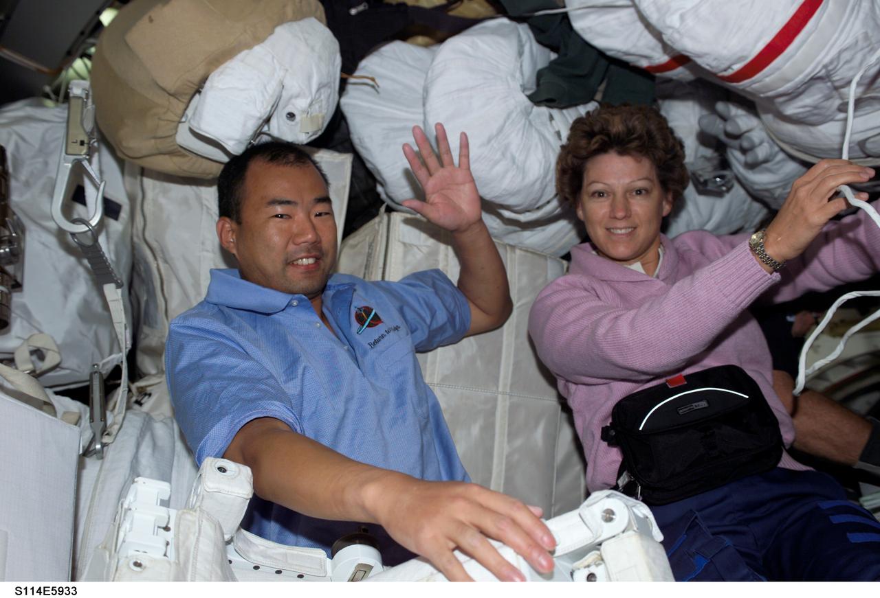 S114-E-5933 (30 July 2005) --- Japan Aerospace Agency astronaut Soichi Noguchi, STS-114 mission specialist, and astronaut Eileen M. Collins, mission commander, share space with spacesuits and other supplies onboard Discovery during activities of Discovery's fifth flight day. Earlier on this day, astronauts Noguchi and Stephen K. Robinson, out of frame, used the NASA extravehicular mobility unit (EMU) spacesuits as they conducted a successful spacewalk.