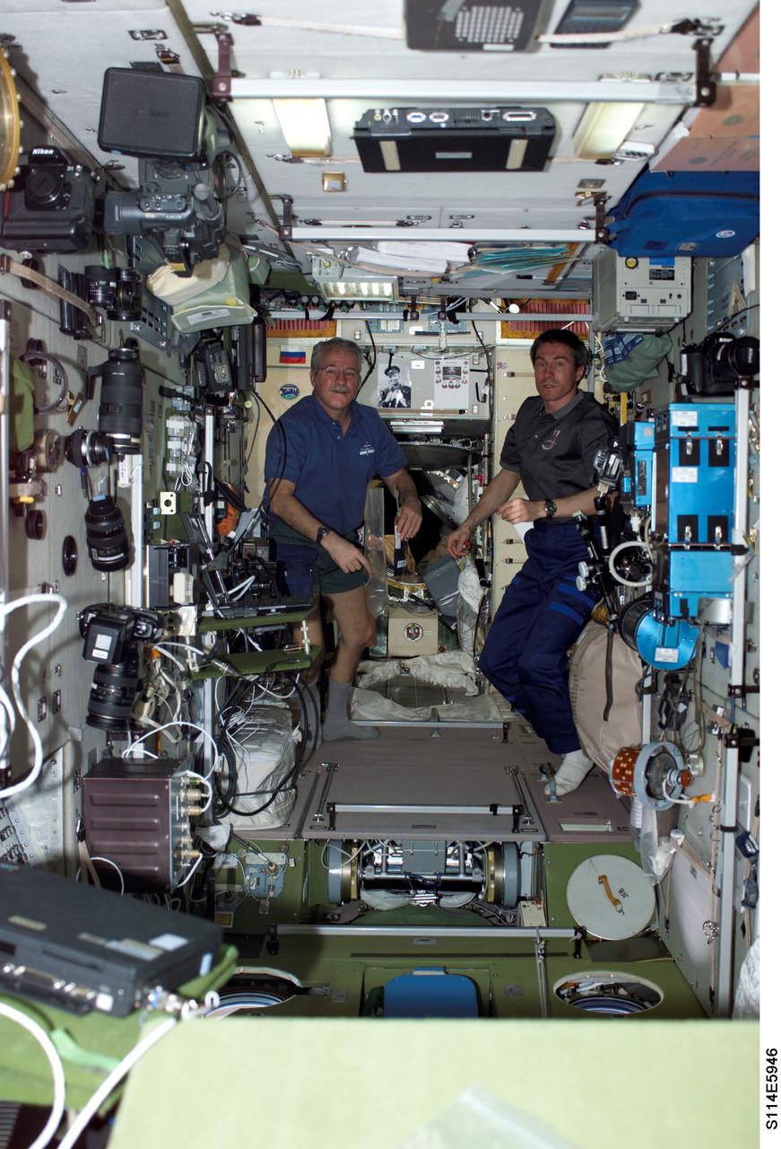 S114-E-5946 (31 July 2005) --- A Sunday morning picture onboard the International Space Station shows the Expedition 11 crew members--John L. Phillips (left) and Sergei Krikalev--in the Zvezda Service Module, while their "guests" from Discovery are at various other locations in the orbital outpost and the Shuttle. Transfer of supplies brought up from Earth still remains one of the high priority activities for the two crews.