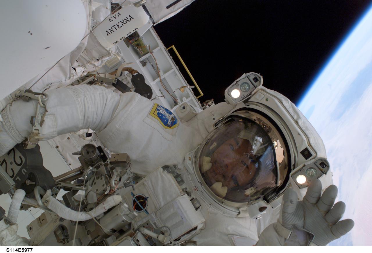 S114-E-5977 (1 August 2005) ---  Japanese Aerospace Exploration Agency astronaut Soichi Noguchi waves at a crewmate, during the August 1 extravehicular activity which he shared with astronaut Stephen K. Robinson.  Earth's horizon, approximately 225 statute miles below, is visible in frame's corner.