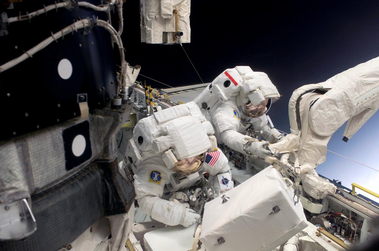S114-E-6059 (30 July 2005) --- Astronaut Stephen K. Robinson (left) and Japan Aerospace Exploration Agency (JAXA) astronaut Soichi Noguchi, both STS-114 mission specialists, work in the Space Shuttle Discovery’s cargo bay during the mission’s first session of extravehicular activity (EVA) while the Shuttle was docked to the international space station.