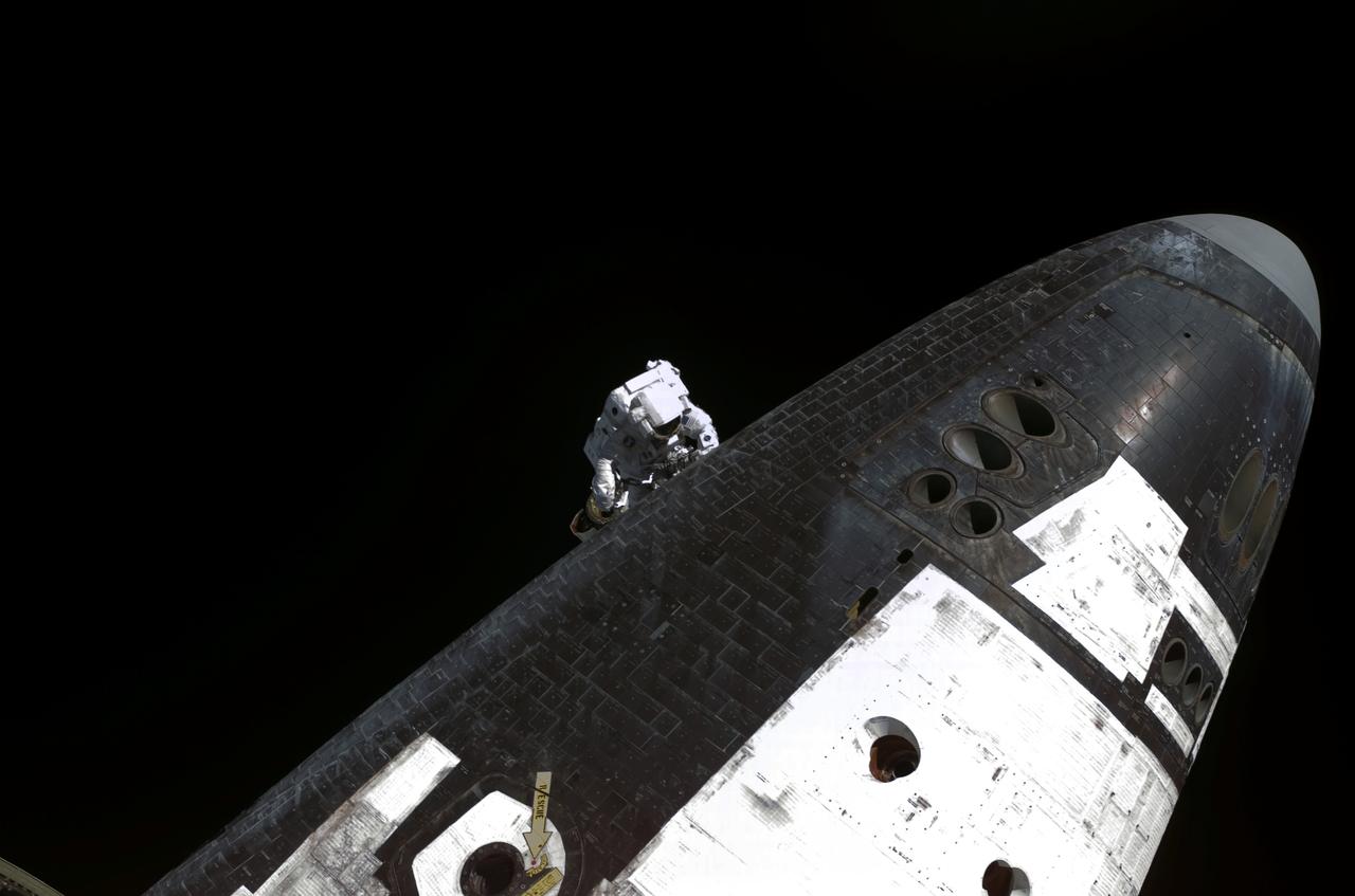 S114-E-6215 (3 August 2005) --- Astronaut Stephen K. Robinson, STS-114 mission specialist, on the end of the station’s Canadarm2 (out of frame), slowly and cautiously makes his way to the underside of Space Shuttle Discovery to remove gap fillers from between the orbiter’s heat-shielding tiles during the mission’s third of three sessions of extravehicular activity (EVA).