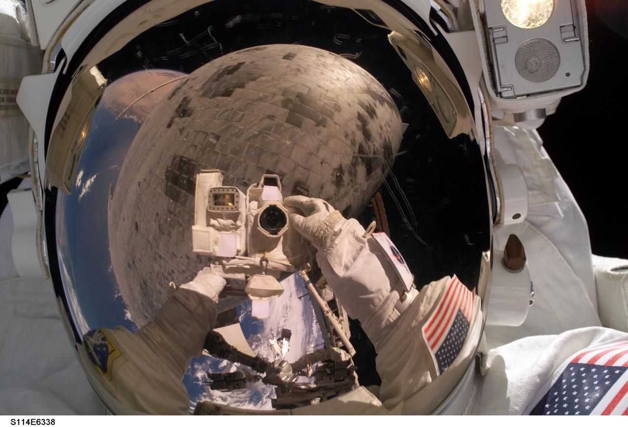 S114-E-6338 (3 August 2005) --- Astronaut Stephen K. Robinson, STS-114 mission specialist, used the pictured digital camera to expose a photo of his helmet visor during today;s extravehicular activities (EVA). Also visible in the reflection are thermal protection tiles on Space Shuttle Discovery;s underside.