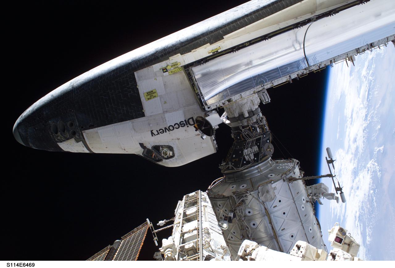 S114-E-6469 (3 August 2005) --- The Space Shuttle Discovery, docked to the Destiny laboratory of International Space Station, is featured in this image photographed by astronaut Stephen K. Robinson (out of frame), STS-114 mission specialist, during todays spacewalk. Astronaut Soichi Noguchi, mission specialist representing Japan Aerospace Exploration Agency (JAXA), is visible at lower right on Destiny. The blackness of space and Earths horizon formed the backdrop for the image.