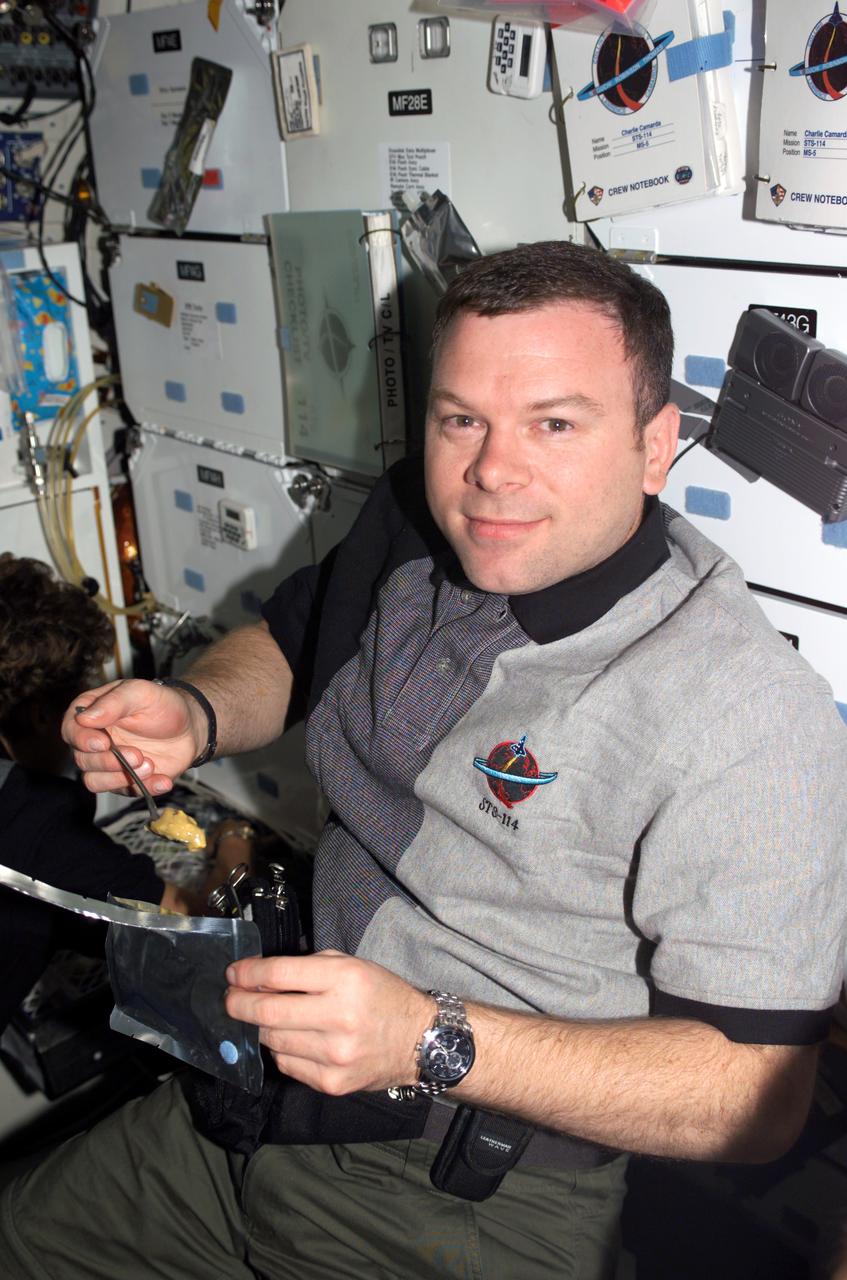 S114-E-6569 (2 August 2005) --- Astronaut James M. Kelly, STS-114 pilot, eats a meal on the middeck of the Space Shuttle Discovery while docked to the international space station.