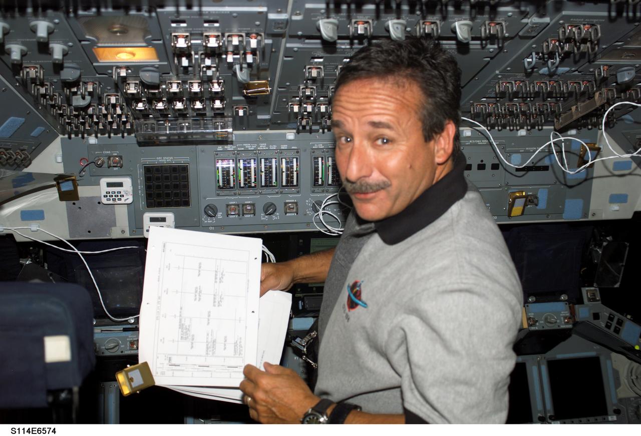S114-E-6574 (3 August 2005) --- Astronaut Charles J. Camarda, STS-114 mission specialist, looks over a procedures checklist on the flight deck of the Space Shuttle Discovery while docked to the International Space Station.