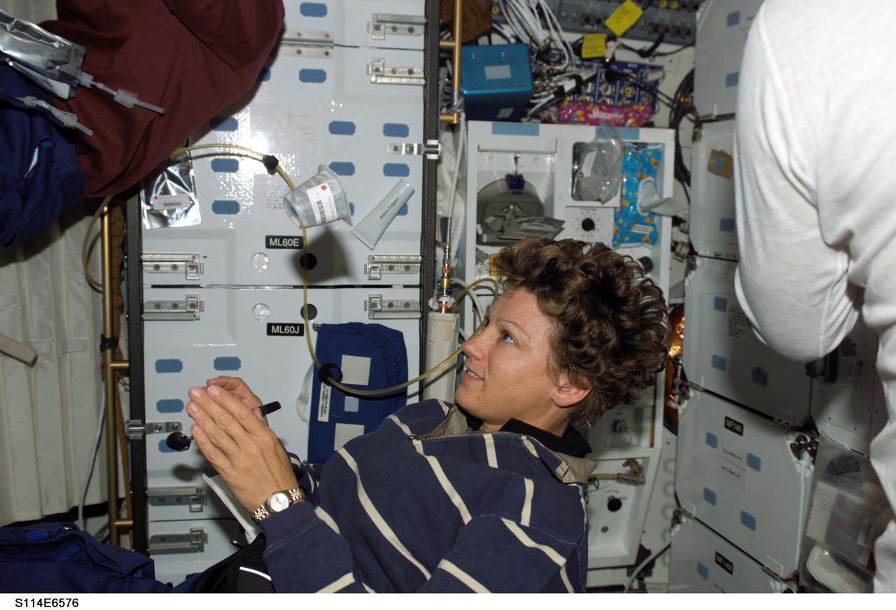 S114-E-6576 (3 August 2005) --- Astronaut Eileen M. Collins, STS-114 commander, watches a container of food floating freely on the middeck of the Space Shuttle Discovery while docked to the International Space Station.