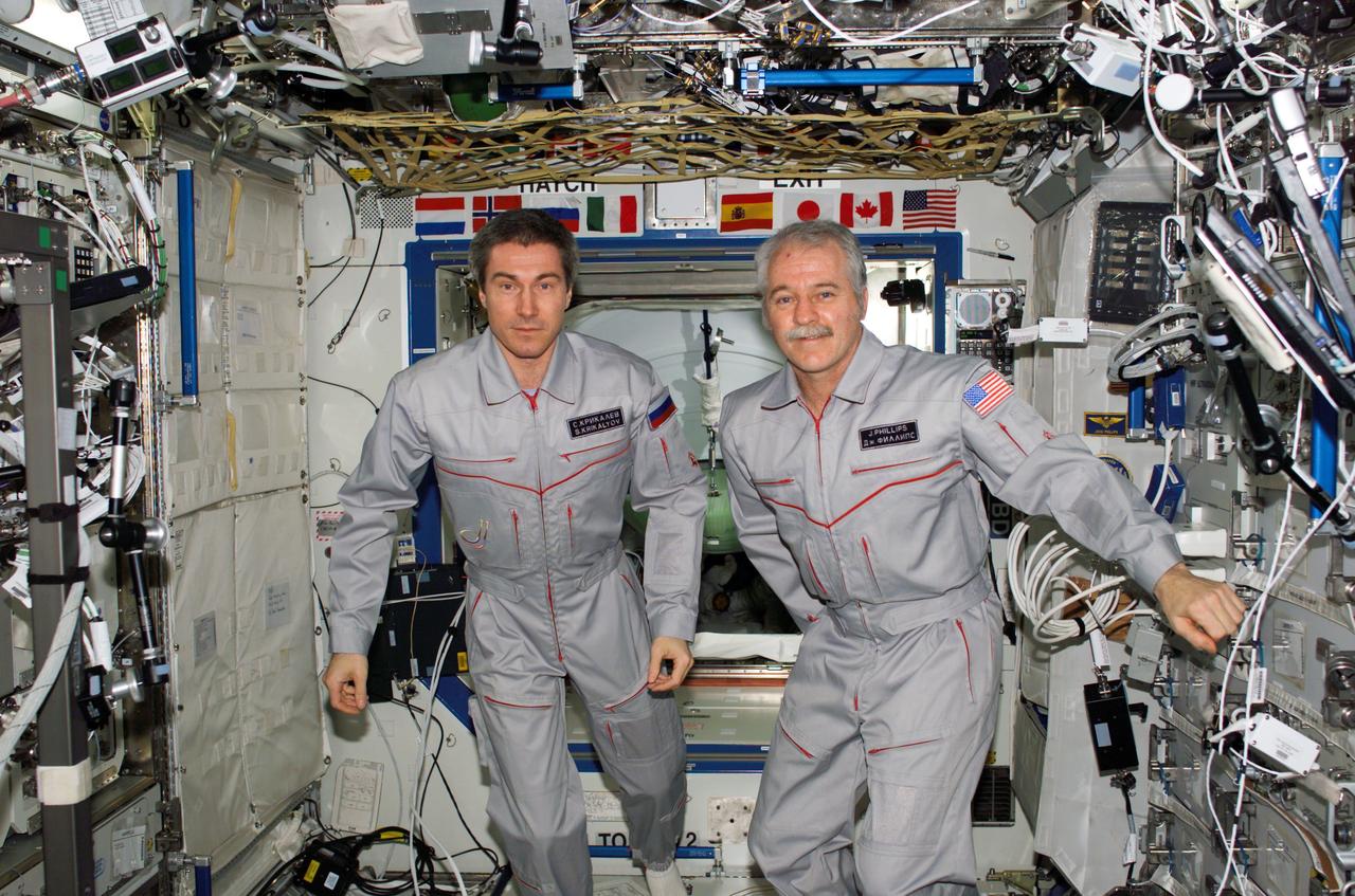 S114-E-6784 (2 August 2005) --- Cosmonaut Sergei K. Krikalev (left), Expedition 11 commander representing Russia's Federal Space Agency, and astronaut John L. Phillips, NASA Space Station science officer and flight engineer, pose for a crew photo in the Destiny laboratory of the International Space Station. At the time, the two were playing host to the seven Discovery crewmembers.