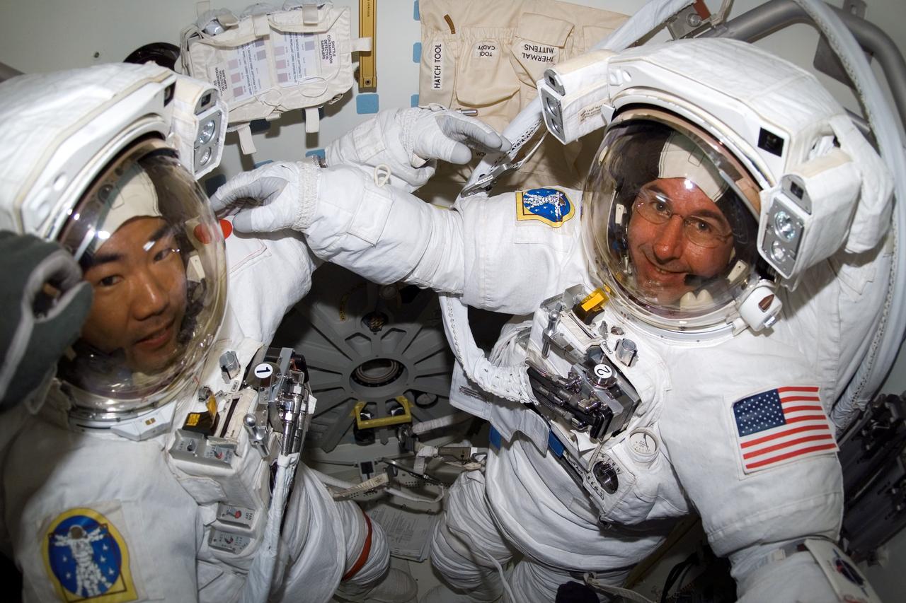 S114-E-6926 (3 August 2005) --- Astronauts Soichi Noguchi (left) representing Japan Aerospace Exploration Agency (JAXA), and Stephen K. Robinson, both STS-114 mission specialists, pose for a photo in the Space Shuttle Discovery;s airlock as the mission;s third session of extravehicular activity (EVA) drew to a close. Robinson and Noguchi are wearing their Extravehicular Mobility Unit (EMU) space suits.