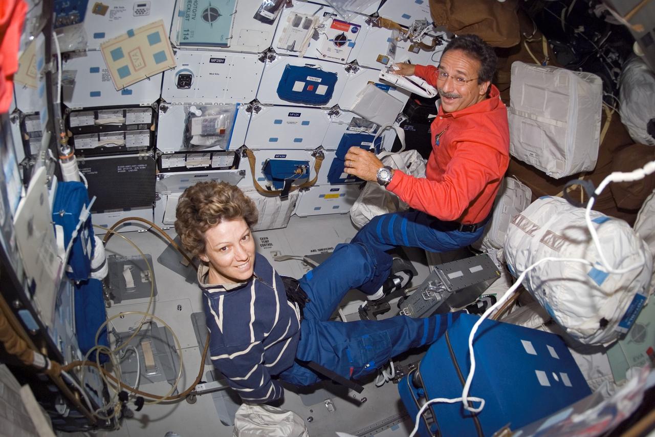 S114-E-6946 (4 August 2005) --- Astronaut Eileen M. Collins, STS-114 commander, works out on the bicycle ergometer on the Space Shuttle Discovery's middeck. Astronaut Charles J. Camarda, mission specialist, works along side Collins.