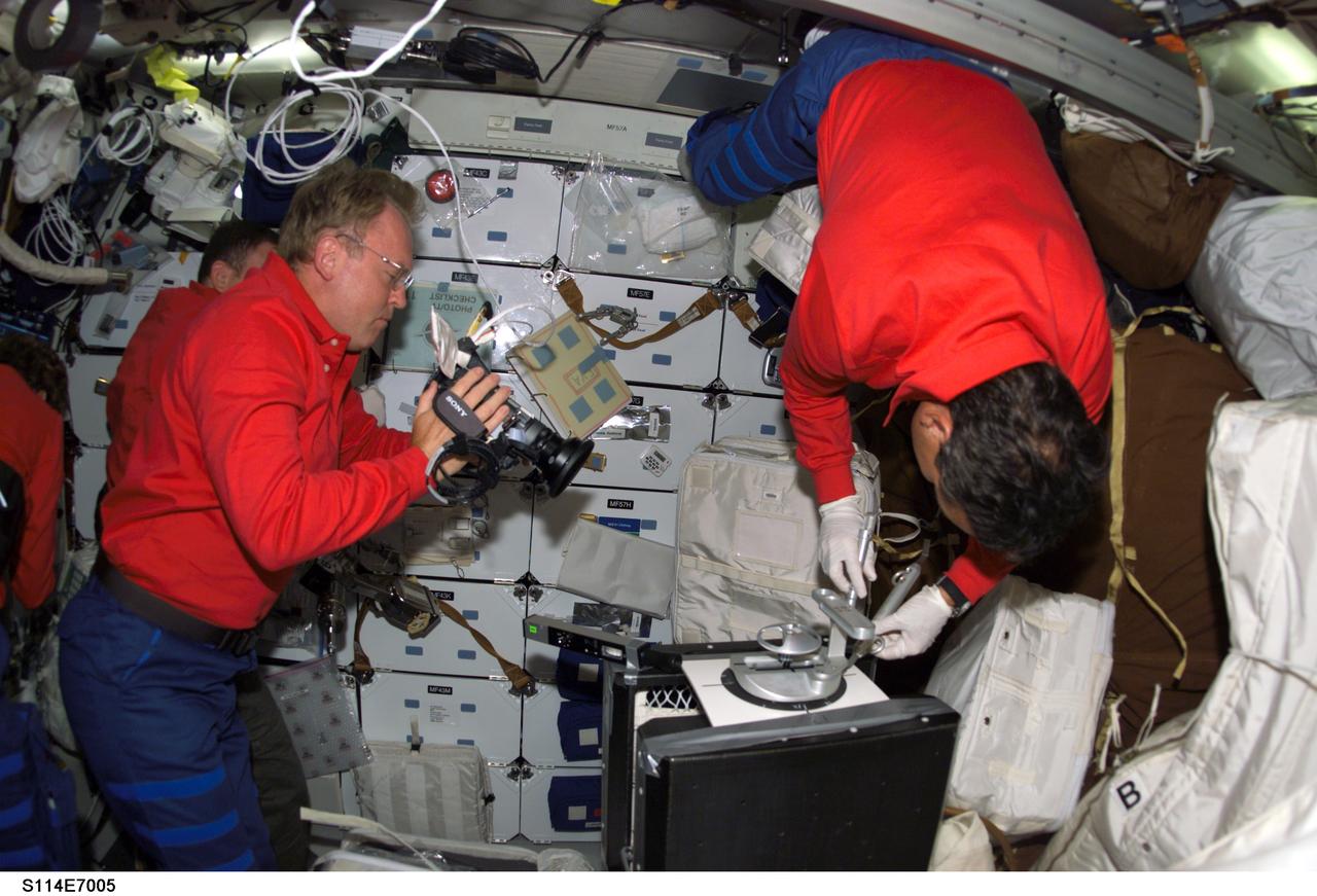 S114-E-7005 (4 August 2005) --- Astronaut Andrew S. W. Thomas, STS-114 mission specialist, photographs a middeck evaluation of the mechanical "plug" option for Reinforced Carbon-Carbon (RCC) repair aboard the Space Shuttle Discovery. Astronaut Charles J. Camarda, mission specialist, uses special pre-designated tools to accomplish the procedure, along with round thin, flexible 7-inch-diamter carbon-silicon cover plates designed to flex up to 0.25 inch to conform to the wing leading edge RCC panels, a hardware attachment mechanism similar to a toggle bolt and sealant.