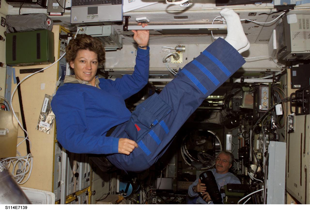 S114-E-7139 (5 August 2005) --- Astronaut Eileen M. Collins, STS-114 commander, floats in the Zvezda Service Module of the International Space Station while Space Shuttle Discovery was docked to the Station. Astronaut John L. Phillips, Expedition 11 NASA Space Station science officer and flight engineer, is visible at bottom right.