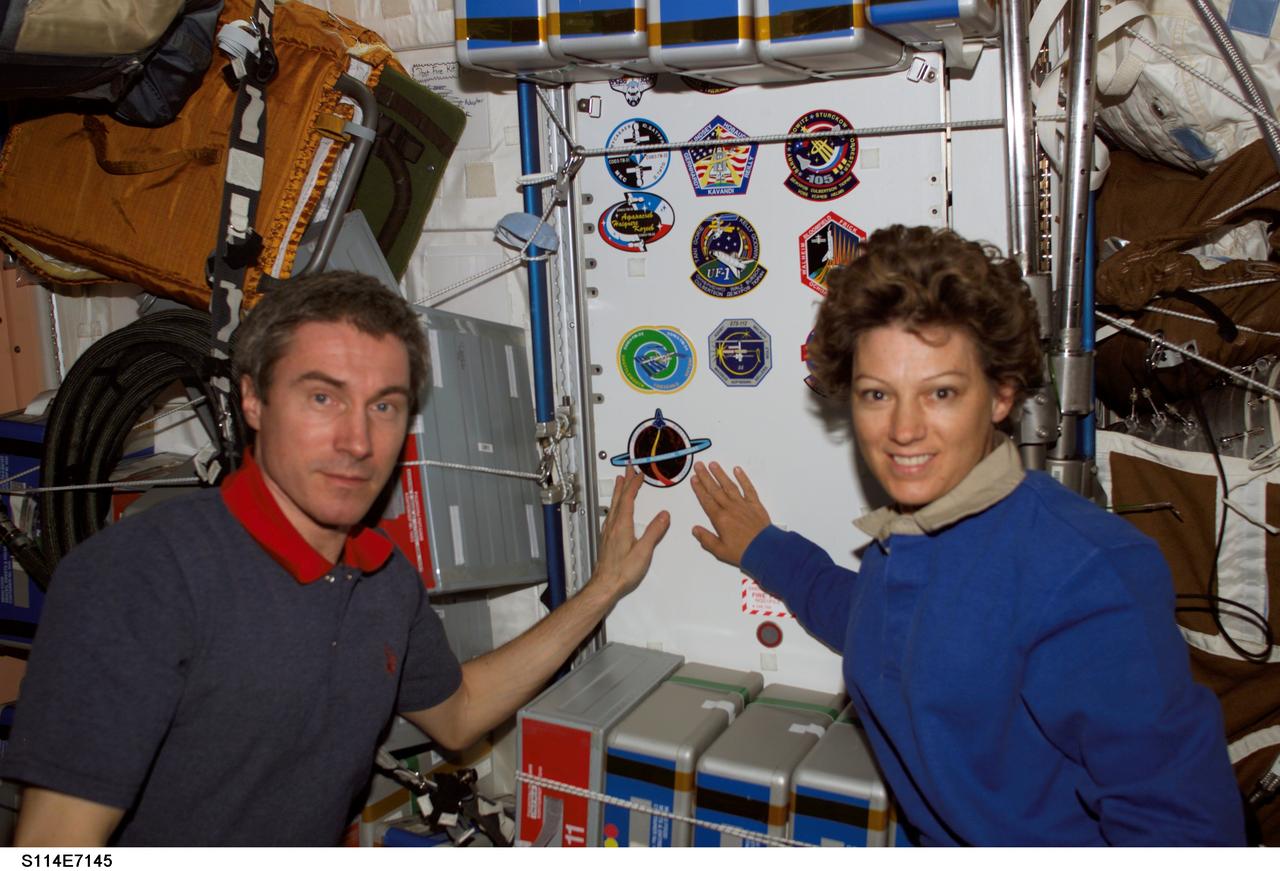 S114-E-7145 (5 August 2005) --- Astronaut Eileen M. Collins (right), STS-114 commander, and cosmonaut Sergei K. Krikalev, Expedition 11 commander representing Russia's Federal Space Agency, pose for a photo in the Unity node after the STS-114 crew patch was added to the growing collection of insignias representing crews who have worked on the International Space Station.