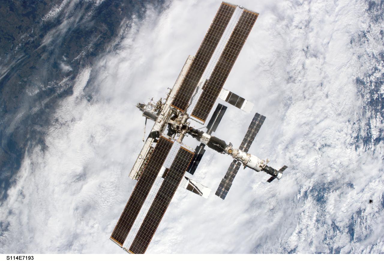 S114-E-7193 (6 August 2005) ---  The International Space Station is backdropped against clouds as it moves away from the Space Shuttle Discovery after the respective crews concluded nine days of cooperative work. Undocking occurred at 2:24 a.m. (CDT), August 6, 2005.