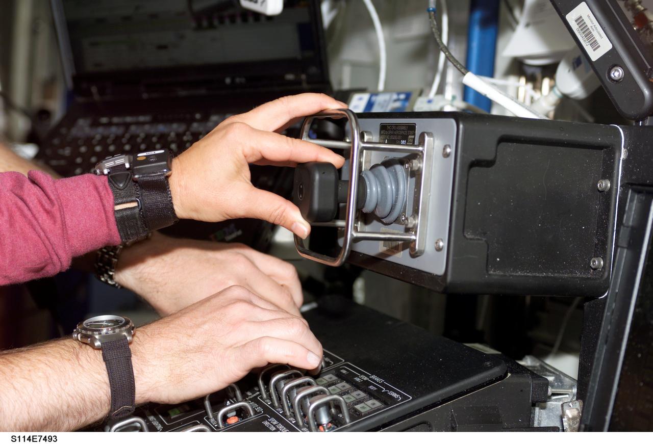 S114-E-7493 (5 August 2005) --- This image features a close-up view the hands of astronauts Wendy B. Lawrence, STS-114 mission specialist, and James M. Kelly, pilot, at the Mobile Service System (MSS) and Canadarm2 controls in the Destiny laboratory of the International Space Station while Space Shuttle Discovery was docked to the Station. The two were re-stowing the Italian-built Raffaello Multi-Purpose Logistics Module (MPLM) in the cargo bay.