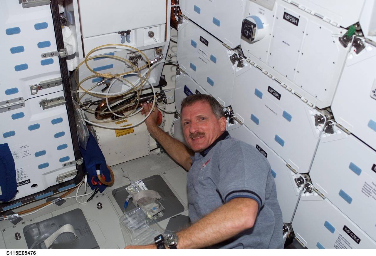 S115-E-05476 (11 Sept. 2006) --- With his hand on a maze of hoses, astronaut Joseph R. Tanner, STS-115 mission specialist, sets up the water system on the mid deck of the Space Shuttle Atlantis.