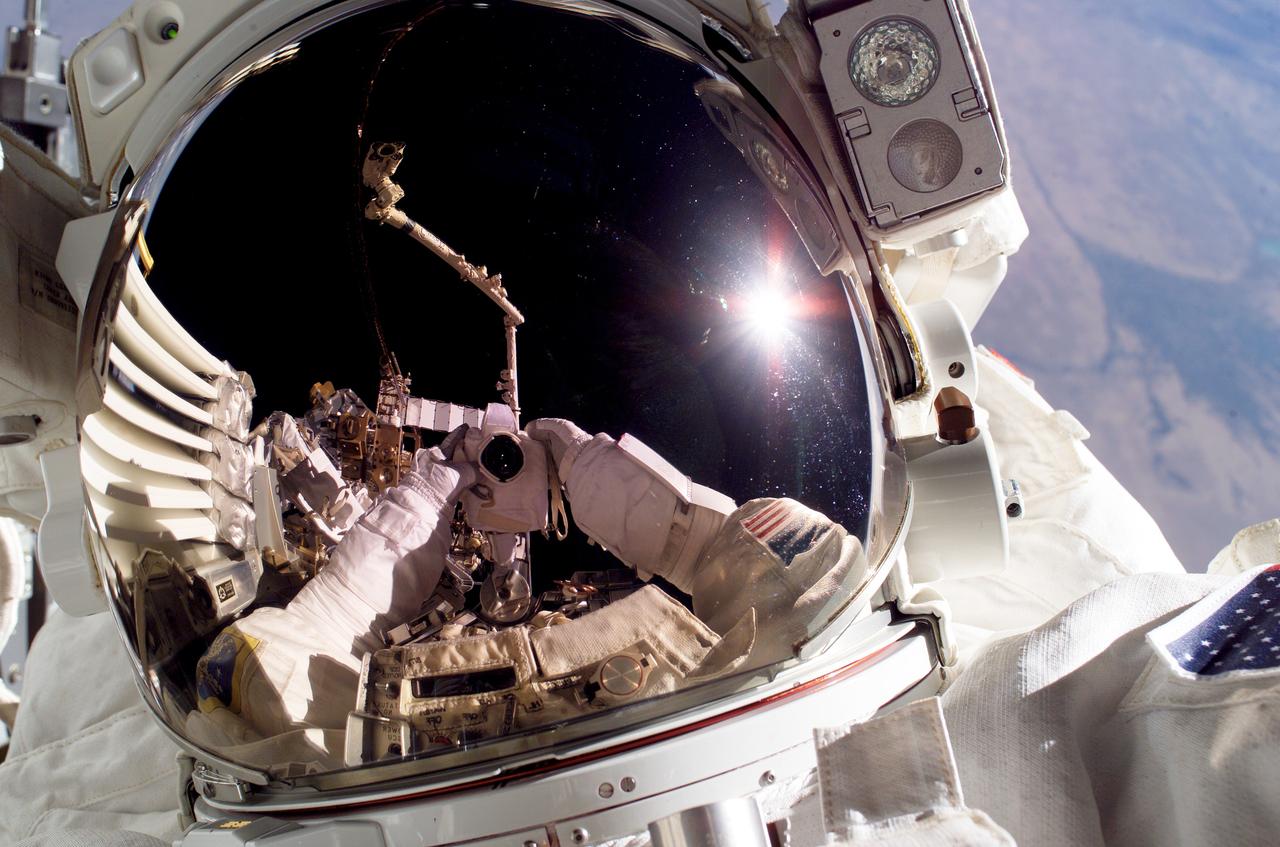 S115-E-05726 (12 Sept. 2006) --- Astronaut Joseph R. Tanner, STS-115 mission specialist, used a digital still camera to expose a photo of his helmet visor during today's session of extravehicular activity (EVA) while Space Shuttle Atlantis was docked with the International Space Station. Also visible in the reflections in the visor is the station's Canadarm2.