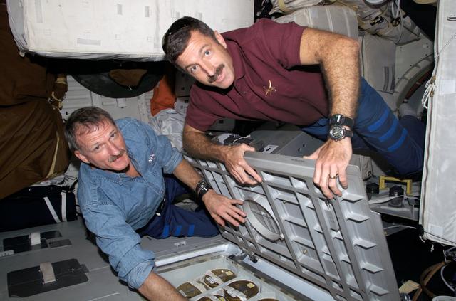 NASA image: Tanner and Burbank store lithium hydroxide canisters beneath the MDDK during Expedition 13 / STS-115 Joint Operations