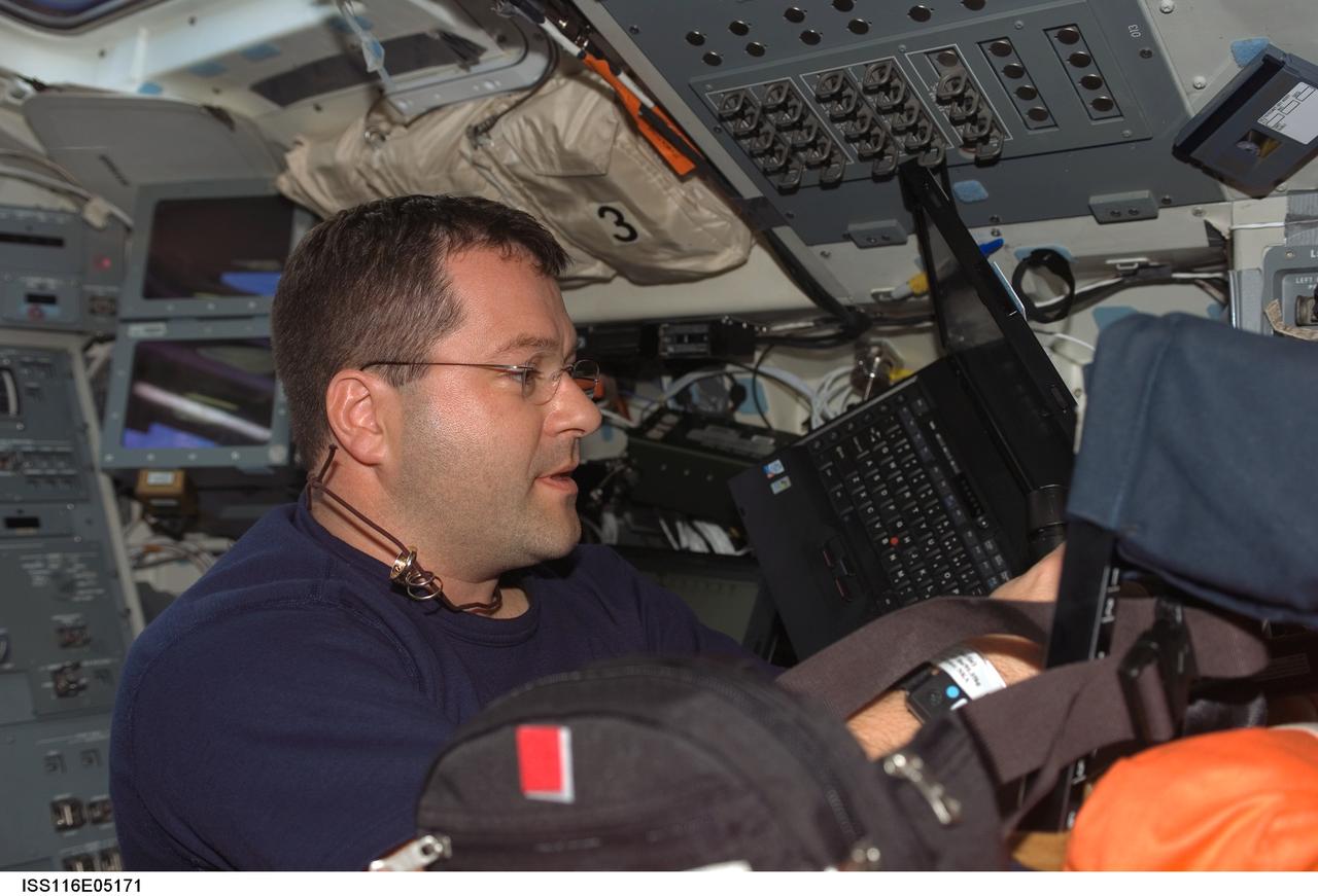 S116-E-05171 (10 Dec. 2006) --- Astronaut Nicholas J. M. Patrick, STS-116 mission specialist, works on the flight deck of Space Shuttle Discovery during flight day two.