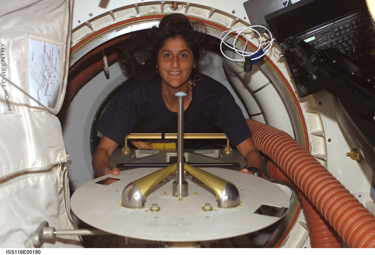 S116-E-05190 (10 Dec. 2006) --- Astronaut Sunita L. Williams, STS-116 mission specialist, moves a hatch cover as she moves from Spacehab to the middeck of Space Shuttle Discovery. Williams will join the Expedition 14 crew as flight engineer after she enters the International Space Station. Docking of the two spacecraft will occur on Dec. 11.