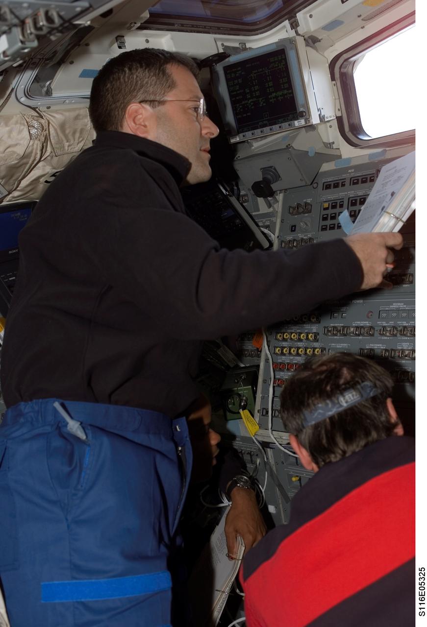 S116-E-05325 (10 Dec. 2006) --- Astronaut Nicholas J. M. Patrick, STS-116 mission specialist, looks over a procedures checklist on the aft flight deck of Space Shuttle Discovery during flight day two activities.