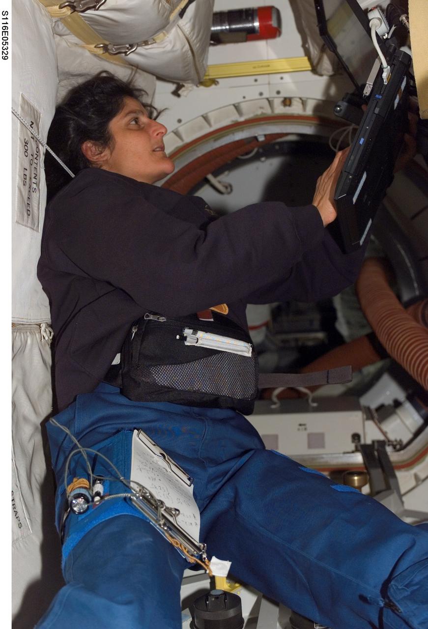 S116-E-05329 (10 Dec. 2006) --- Astronaut Sunita L. Williams, STS-116 mission specialist, uses a computer on the middeck of Space Shuttle Discovery during flight day two activities.