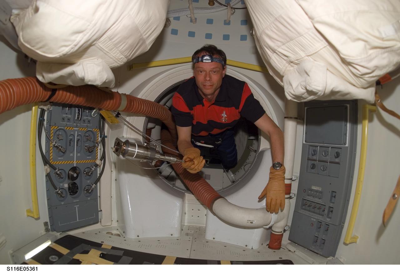 S116-E-05361 (10 Dec. 2006) --- European Space Agency (ESA) astronaut Christer Fuglesang, STS-116 mission specialist, holds a tool as he floats through a hatch on Space Shuttle Discovery during flight day two activities.
