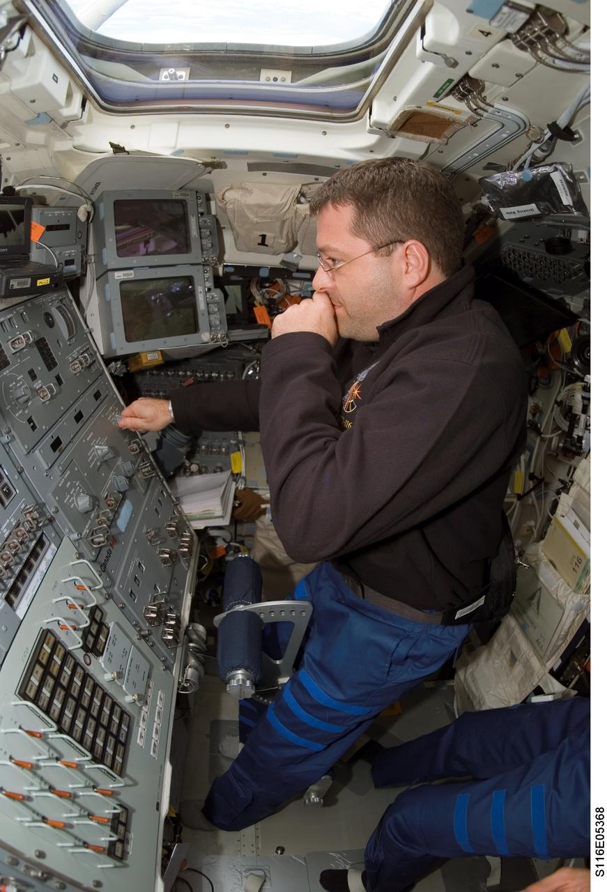 S116-E-05368 (10 Dec. 2006) --- Astronaut Nicholas J. M. Patrick, STS-116 mission specialist, works controls on the aft flight deck of Space Shuttle Discovery during flight day two activities.