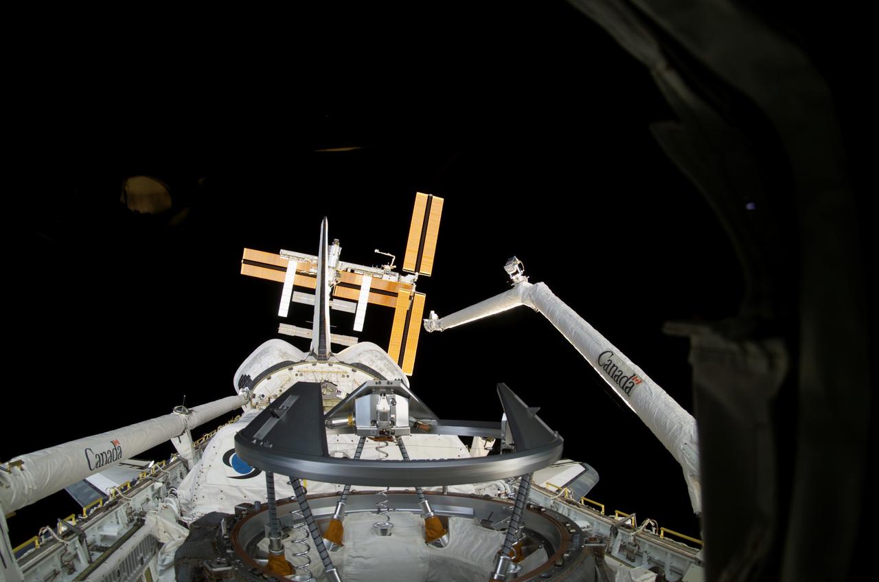 S116-E-05504 (11 Dec. 2006) --- As seen through windows on the aft flight deck of Space Shuttle Discovery, the shuttle's payload bay and the approaching International Space Station (background) are featured in this image photographed by a STS-116 crewmember during flight day three activities. Pictured in the payload bay are the shuttle's docking mechanism (foreground), Spacehab module (partially obscured), the Canadian-built Remote Manipulator System (RMS) robotic arm (right), and the Remote Manipulator System/Orbiter Boom Sensor System (left, in stowed position).