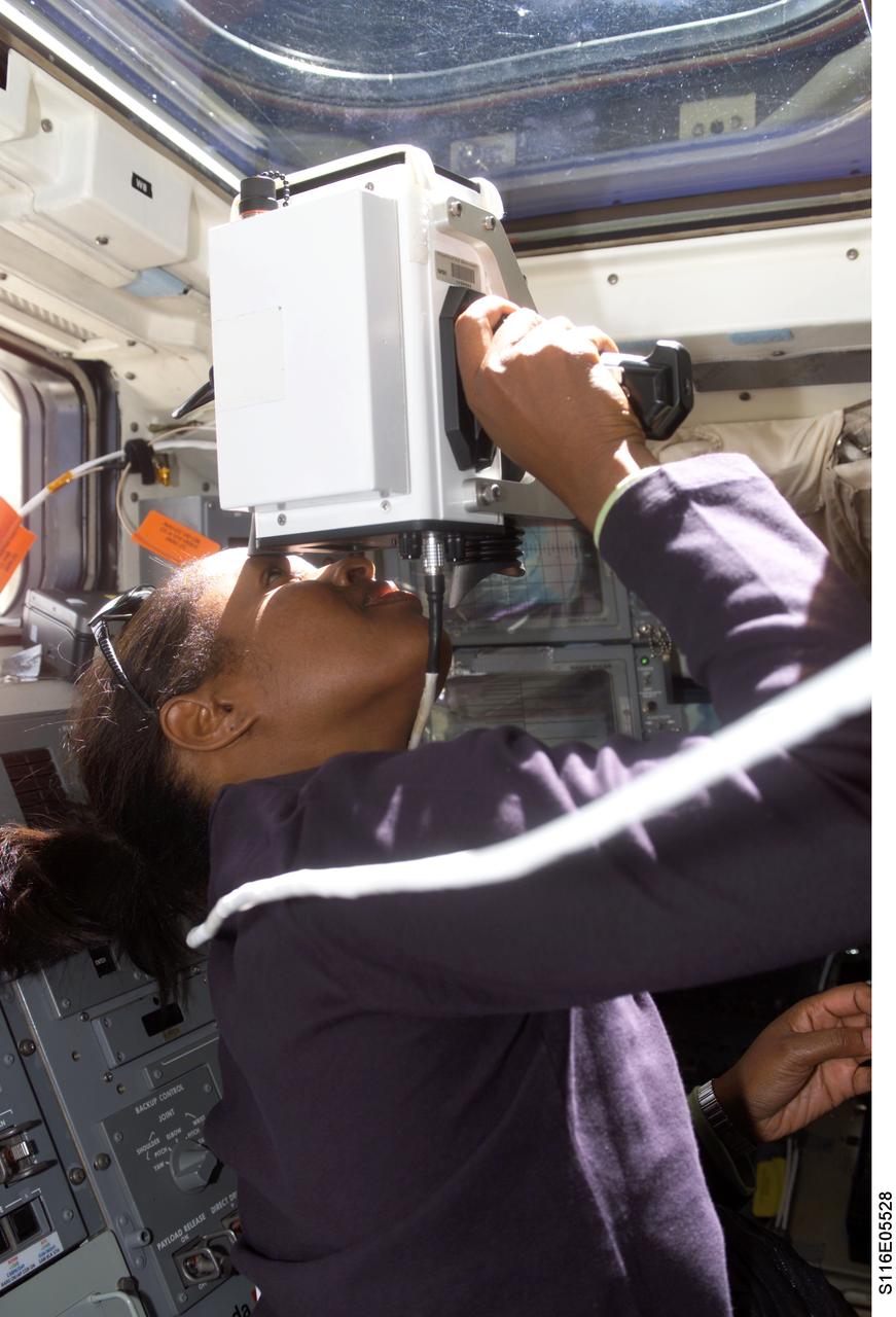 S116-E-05528 (11 Dec. 2006) --- Astronaut Joan E. Higginbotham, STS-116 mission specialist, uses a handheld laser ranging device on the aft flight deck of the Space Shuttle Discovery to track the range of the International Space Station during rendezvous operations.