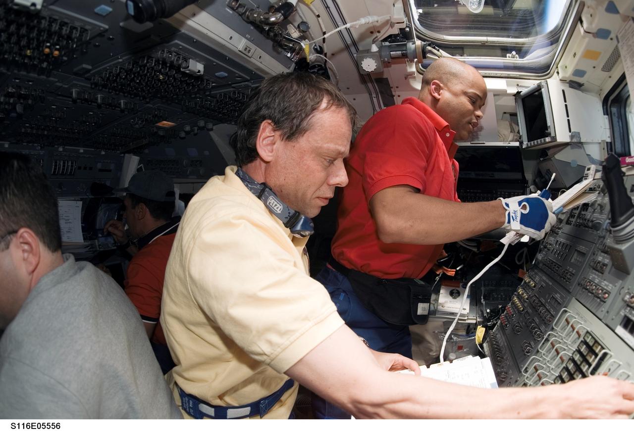 S116-E-05556 (11 Dec. 2006) --- European Space Agency (ESA) astronaut Christer Fuglesang (foreground) and Robert L. Curbeam, Jr., both STS-116 mission specialists, work with controls on the aft flight deck of Space Shuttle Discovery during flight day three activities.