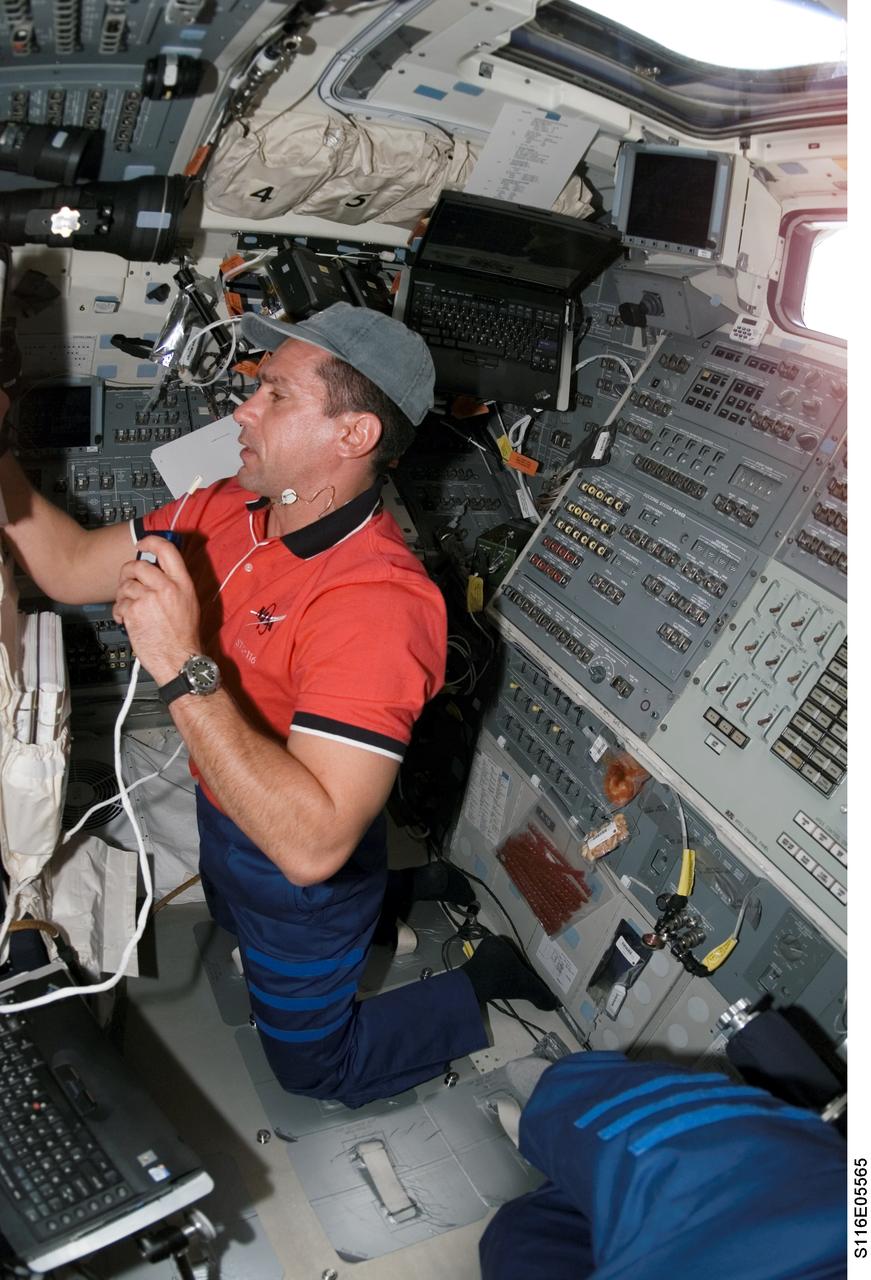 S116-E-05565 (11 Dec. 2006) --- Astronaut William A. (Bill) Oefelein, STS-116 pilot, uses a communication system while looking at a procedures checklist (out of frame) on the aft flight deck of Space Shuttle Discovery during flight day three activities.