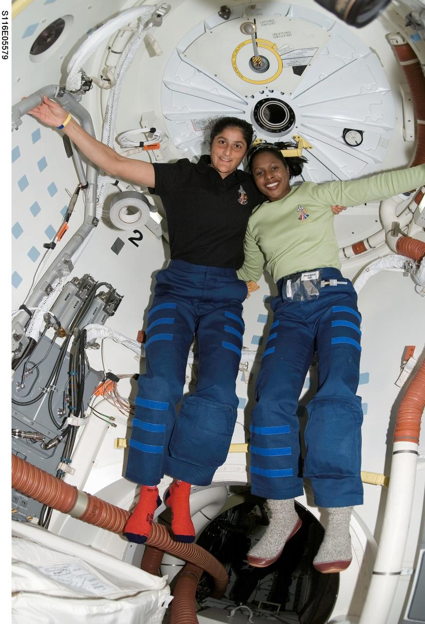 S116-E-05579 (11 Dec. 2006) --- Astronaut Sunita L. Williams (left) and Joan E. Higginbotham, both STS-116 mission specialists, float arm-in-arm near Space Shuttle Discovery's hatch, which leads into the International Space Station. Rendezvous and docking operations between the shuttle and station occurred at 4:12 p.m. (CST) and the crew entered the orbital outpost at 5:54 p.m. (CST) on Dec. 11.