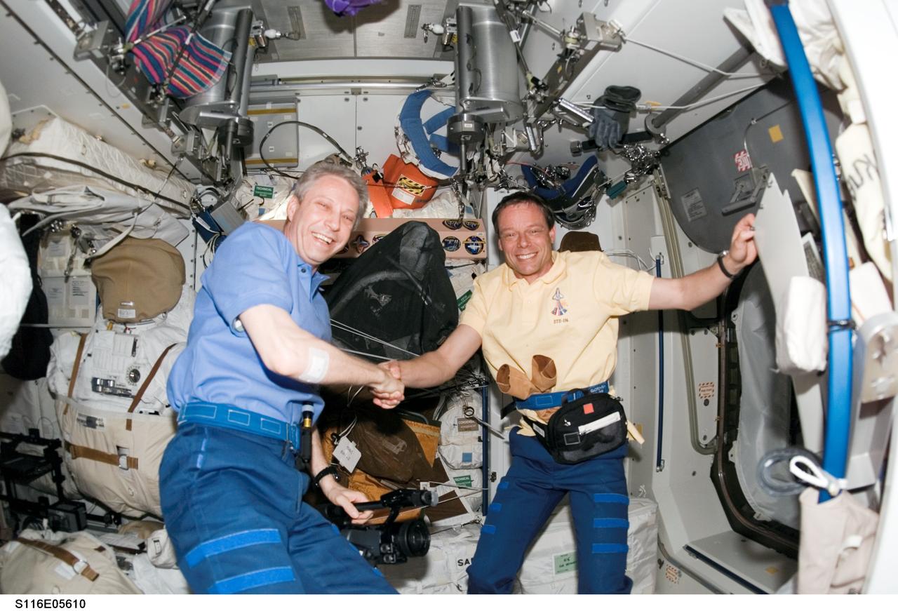 S116-E-05610 (11 Dec. 2006) --- European Space Agency (ESA) astronauts Thomas Reiter (left), Expedition 14 flight engineer, and Christer Fuglesang, STS-116 mission specialist, exchange greetings in the International Space Station following a successful rendezvous and docking between the station and shuttle.