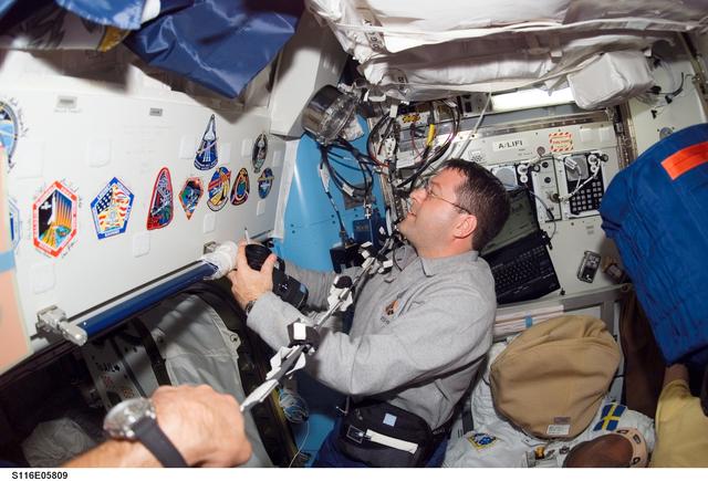 NASA image: STS-116 MS Patrick looks at STS-116 Patch in the Airlock