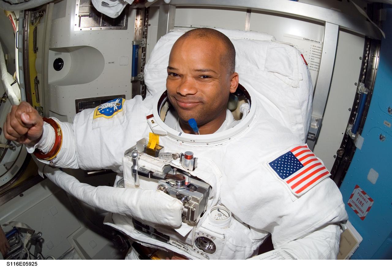 S116-E-05925 (12 Dec. 2006) --- As the mission's first spacewalk draws to a close, astronaut Robert L. Curbeam, Jr., STS-116 mission specialist, smiles for the camera in the Quest Airlock of the International Space Station.