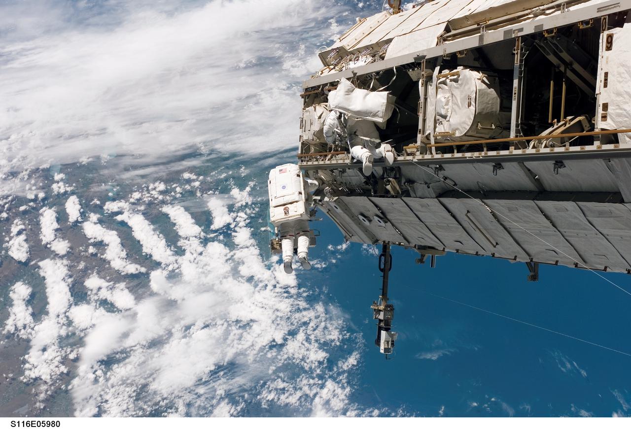 S116-E-05980 (12 Dec. 2006) --- Backdropped by a colorful Earth, including land mass that covers parts of New Zealand, astronaut Robert L. Curbeam, Jr. (left) and European Space Agency (ESA) astronaut Christer Fuglesang, both STS-116 mission specialists, participate in the mission's first of three planned sessions of extravehicular activity (EVA) as construction resumes on the International Space Station. Photo credit: NASA