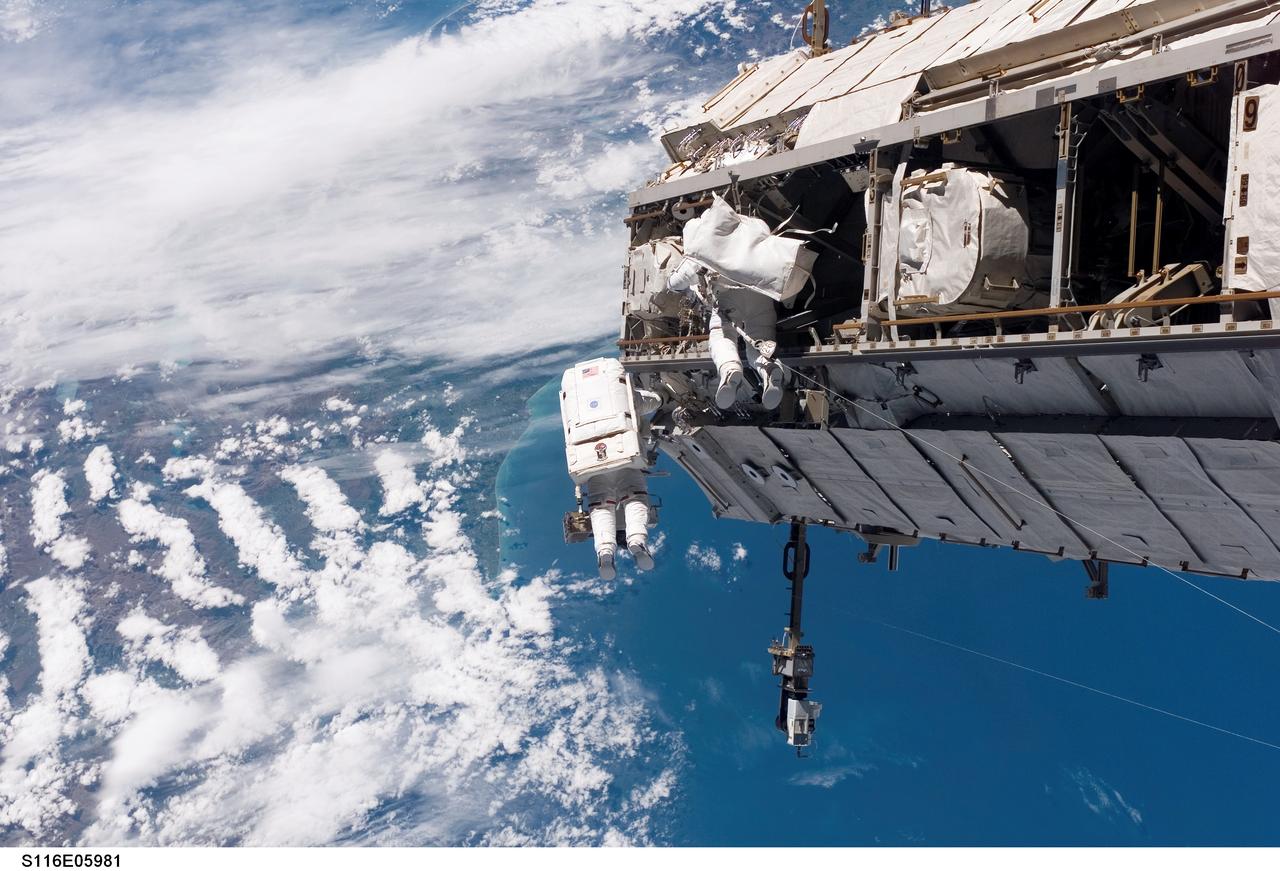 S116-E-05981 (12 Dec. 2006) --- Backdropped by a colorful Earth, including land mass that covers parts of New Zealand, astronaut Robert L. Curbeam, Jr. (left) and European Space Agency (ESA) astronaut Christer Fuglesang, both STS-116 mission specialists, participate in the mission's first of three planned sessions of extravehicular activity (EVA) as construction resumes on the International Space Station. Photo credit: NASA