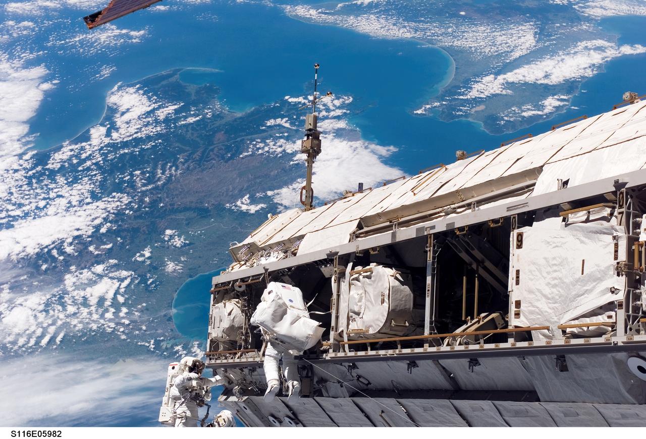 S116-E-05982 (12 Dec. 2006) --- Backdropped by a colorful Earth, including land mass that covers parts of New Zealand, astronaut Robert L. Curbeam, Jr. (left) and European Space Agency (ESA) astronaut Christer Fuglesang, both STS-116 mission specialists, participate in the mission's first of three planned sessions of extravehicular activity (EVA) as construction resumes on the International Space Station. Photo credit: NASA