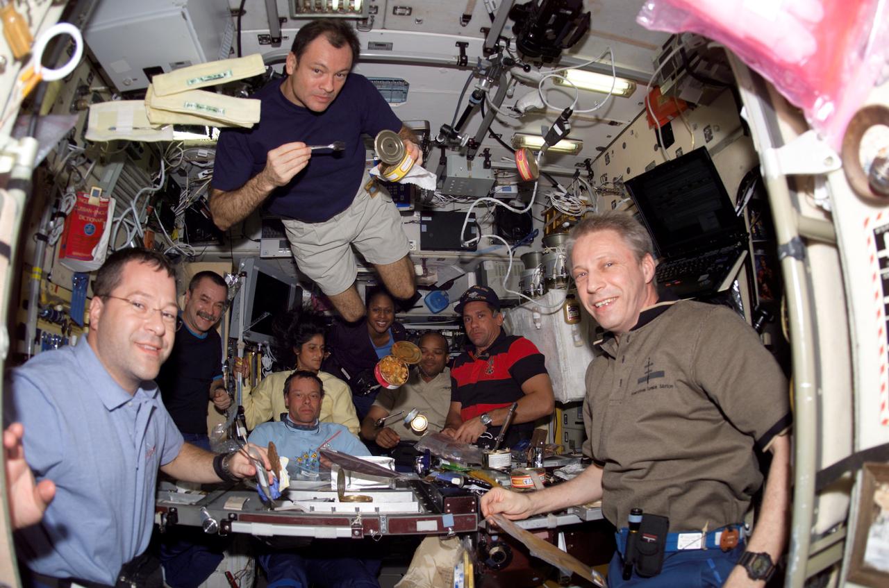 S116-E-06068 (13 Dec. 2006) --- The STS-116 and Expedition 14 crewmembers share a meal in the Zvezda Service Module of the International Space Station. Pictured in the foreground are astronauts Nicholas J. M. Patrick (left), STS-116 mission specialist; Michael E. Lopez-Alegria (center top), Expedition 14 commander and NASA space station science officer; and European Space Agency (ESA) astronaut Thomas Reiter (right), STS-116 mission specialist. Pictured in the background are cosmonaut Mikhail Tyurin (left), Expedition 14 flight engineer representing Russia's Federal Space Agency; European Space Agency (ESA) astronaut Christer Fuglesang, STS-116 mission specialist; Sunita L. Williams, Expedition 14 flight engineer; Joan E. Higginbotham, Robert L. Curbeam, Jr., both STS-116 mission specialists; and William A. (Bill) Oefelein, STS-116 pilot. Astronaut Mark L. Polansky, STS-116 commander, is out of frame.