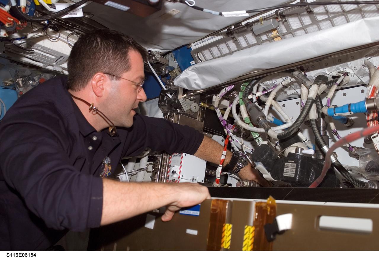 S116-E-06154 (14 Dec. 2006) --- Astronaut Nicholas J. M. Patrick, STS-116 mission specialist, works in the Destiny laboratory of the International Space Station while Space Shuttle Discovery was docked with the station.