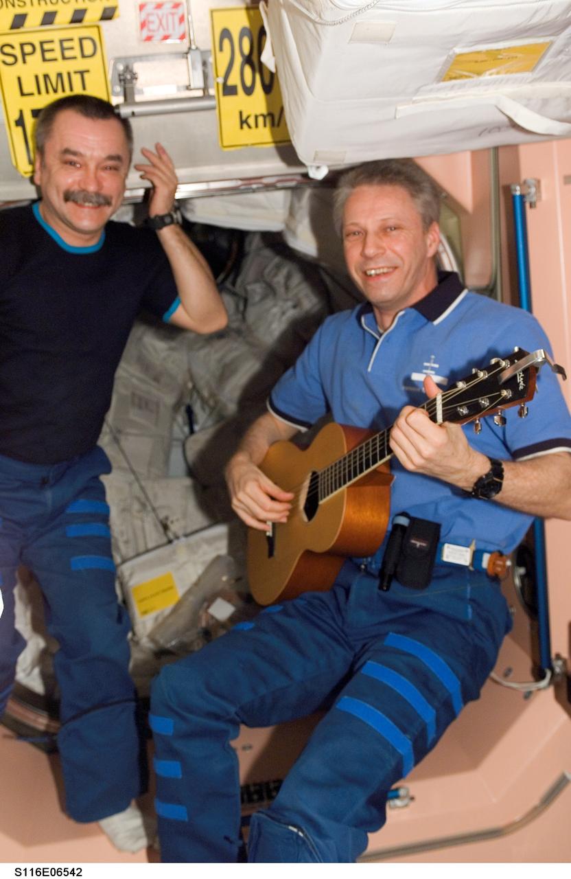 S116-E-06542 (15 Dec. 2006) --- European Space Agency (ESA) Thomas Reiter (right), STS-116 mission specialist, plays a guitar in the Unity node of the International Space Station. Cosmonaut Mikhail Tyurin, Expedition 14 flight engineer representing Russia's Federal Space Agency, is at left.