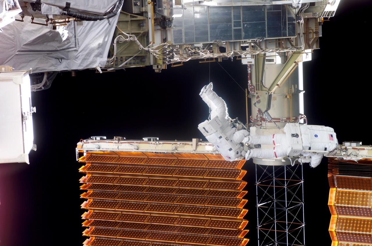 S116-E-06603 (16 Dec. 2006) --- Astronauts Robert L. Curbeam, Jr., (red stripes), STS-116 mission specialist, and Sunita L. Williams, Expedition 14 flight engineer, work near the International Space Station's left P6 solar array wing during the mission's third planned session of extravehicular activity (EVA) as construction resumes on the International Space Station.